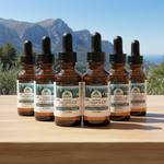 Bottles of oregano oil with droppers on a wooden surface with a mountainous background